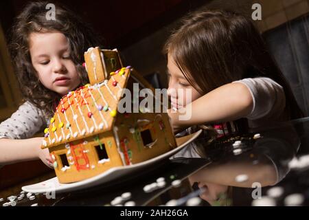 Kinder, die ihren Ersten Gingerbread House Stockfoto