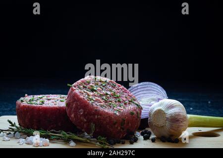Raw organic beaf Steak tartare Burger patty mit Zwiebel, Knoblauch, Thymian, Pfeffer und Himalaya Kristallsalz Stockfoto