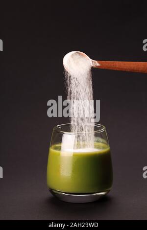 Grüner Saft mit Löffel von Protein oder Kollagen. Nahrungsergänzungsmittel Konzept Stockfoto