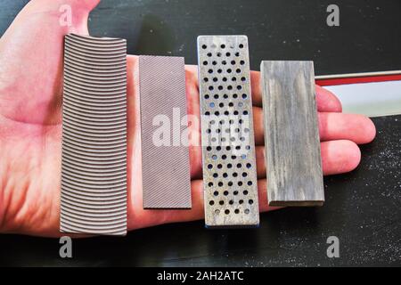 Ski tuning Dateien und Steine in einer Hand: panzar (Panzer) Datei, Mühle Datei, Diamant Stein, Keramik Stein. Diese sind für Ski und Snowboard Kante verwendet Tuning Stockfoto