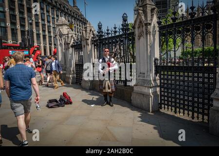 Ein Mann spielt Dudelsack vor dem Parlamentsgebäude und Big Ben in London, UK, GB, England Stockfoto