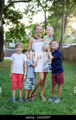 Junge Frau mit Kleinkind Mädchen und drei Jungen im Sommer Park. Mutter und Kinder im Freien. Stockfoto