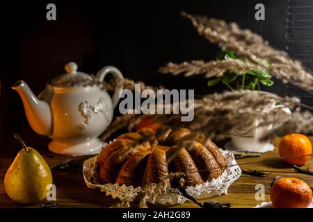 Rustikale italienische Weihnachtskuchen pandoro mit Kaffee, weiß schäbig Teekanne und Früchte auf schwarzem Hintergrund auf dem Schwarzen Brett. Stockfoto