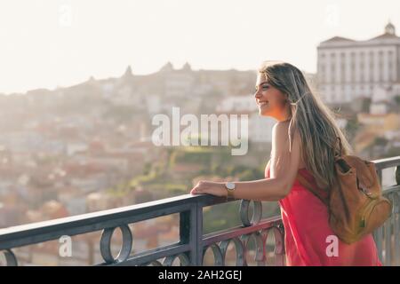 Junge Frau touristische Landschaft genießen Sie einen wunderschönen Blick auf die Altstadt mit Blick auf den Fluss und den berühmten Iron Bridge bei Sonnenuntergang in Porto, Portugal Stockfoto