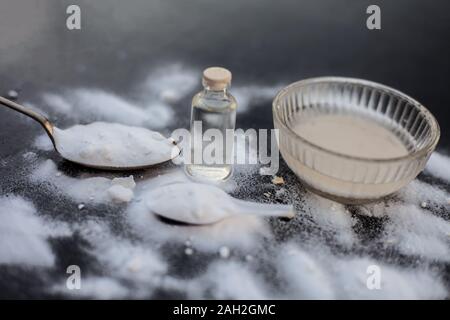 Gesichtsmaske oder Packung Backpulver in eine Glasschüssel auf Holz- Oberfläche zusammen mit Pulver und einige Kokosöl in einem Glasfläschchen. Verwendet für Stockfoto