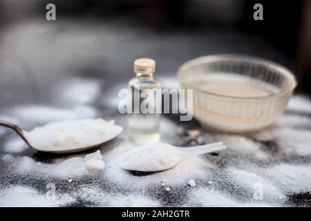 Gesichtsmaske oder Packung Backpulver in eine Glasschüssel auf Holz- Oberfläche zusammen mit Pulver und einige Kokosöl in einem Glasfläschchen. Verwendet für Stockfoto