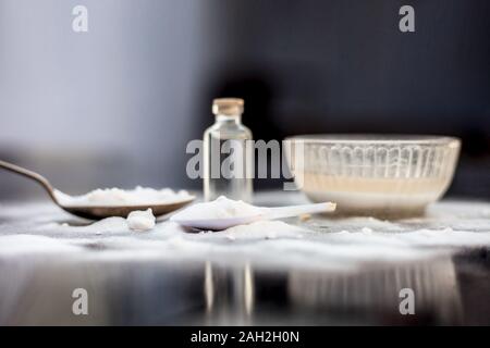 Gesichtsmaske oder Packung Backpulver in eine Glasschüssel auf Holz- Oberfläche zusammen mit Pulver und einige Kokosöl in einem Glasfläschchen. Verwendet für Stockfoto