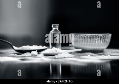 Gesichtsmaske oder Packung Backpulver in eine Glasschüssel auf Holz- Oberfläche zusammen mit Pulver und einige Kokosöl in einem Glasfläschchen. Verwendet für Stockfoto