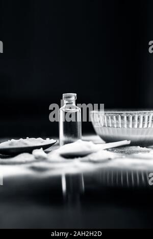 Gesichtsmaske oder Packung Backpulver in eine Glasschüssel auf Holz- Oberfläche zusammen mit Pulver und einige Kokosöl in einem Glasfläschchen. Verwendet für Stockfoto