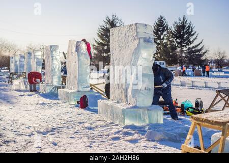 Russland, Birabidzhan, Dezember 18, 2019: die Menschen zerkleinert Eis Skulptur mit einer Kettensäge Stockfoto