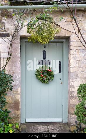 Weihnachten stechpalmen Kranz und Mistel auf einer Hütte Tür in Arlington Row. Bibury, Cotswolds, Gloucestershire, England Stockfoto