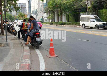 Bangkok, Thailand-December 23, 2019: Ein weiblicher Fahrgast sitzen auf sozius eines Motorrades Taxi immer bereit für eine Fahrt am Motorrad Taxi Warteschlange. Stockfoto