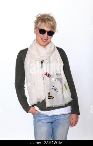 Lächelnde blonde Frau mit Sonnenbrille und Schal gegen den weißen Hintergrund posiert, Portrait. Stockfoto