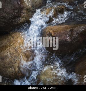 Wasser fließt durch Felsbrocken in einem Stream. Stockfoto