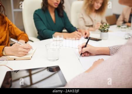 Group of unrecognizable businesswomen working together on new project sitting together at table in office room horizontal shot Stockfoto