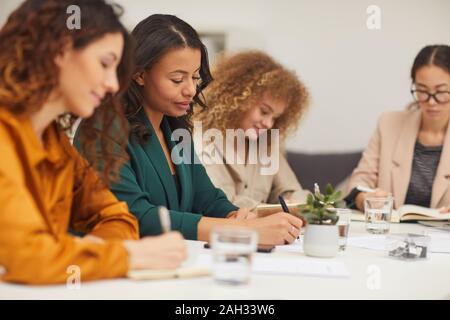 Gruppe von vier erfolgreichen multi-ethnischen Unternehmerinnen arbeiten im Team zusammen zu sitzen in modernen Büro Zimmer Stockfoto