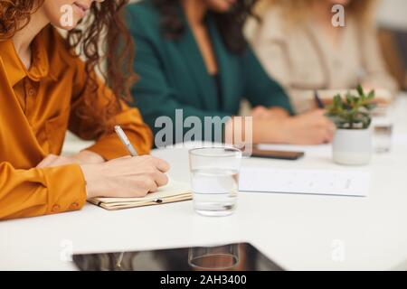 Horizontale Schuß von drei unkenntlich junge Frauen zusammen am Tisch sitzen, sich Notizen während der Sitzung Stockfoto