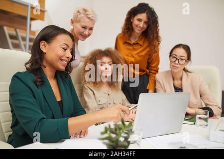 Gruppe von fünf attraktiven weiblichen Büroangestellten etwas aufpassen auf Laptop während der Konferenz Stockfoto