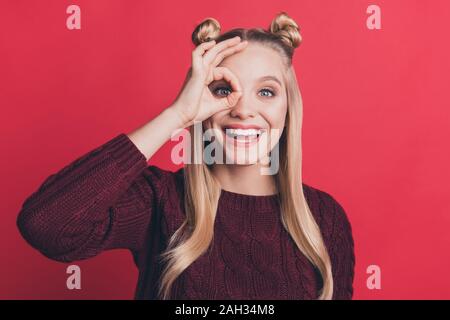 Nahaufnahme der hübschen Dame zeigt okey Symbole in der Nähe von Augen in specs Form weit weg suchen Verschleiß Strickpullover isoliert Pastell rot Farbe Hintergrund Stockfoto