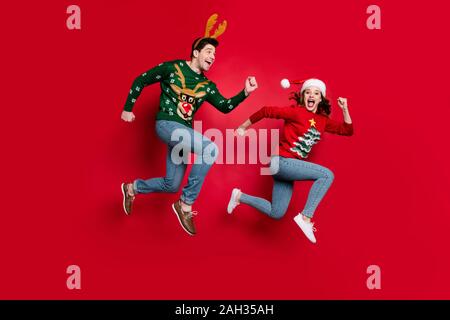 Voller Körper Foto von überrascht springen Paar von x-mas Preise eile Shopping tragen hässliche ornament Jumper rot Farbe Hintergrund isoliert aufgeregt Stockfoto