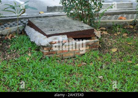 Closeup und auf gebrochene Mauer mit der Bohrung der Ablassschraube auf grünem Gras Feld Fokus Stockfoto