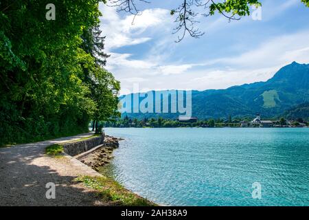 Steg am Rand der türkisfarbenen See namens Wolfgangsee Berge im Hintergrund und Wolken am Himmel Stockfoto