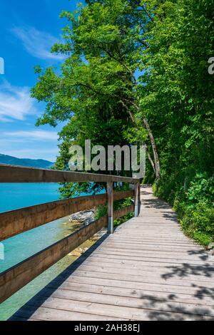 Steg am Rand der türkisfarbenen See namens Wolfgangsee Berge im Hintergrund und Wolken am Himmel Stockfoto