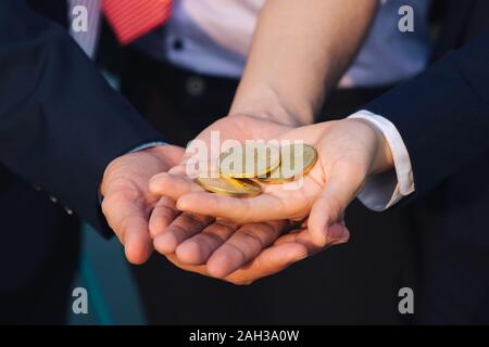Junge asiatische Geschäftsmann und Goldene bitcoin vor seinem Internationalen multi-ethnische Teams in der modernen Stadt. Stockfoto