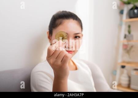 Asiatische Frau erhält das große Geld! Attraktive Frau mit Vormerkungen bitcoin in der Hand und sieht in die Kamera. Stockfoto