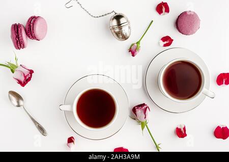 Frühstück Tee am weißen Tisch mit Rosen und Makronen für Zwei. Vallentines Tag und Romantik Konzept. Flach, von oben nach unten Stockfoto