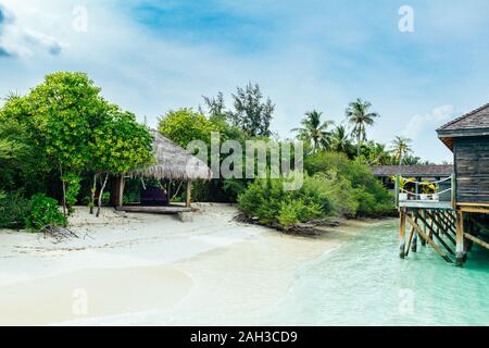 Bungalows und Häuser auf den Malediven mit wunderschönen türkisen Meer und Wolken im Himmel Stockfoto