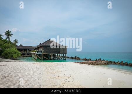 Bungalows und Häuser auf den Malediven mit wunderschönen türkisen Meer und Wolken im Himmel Stockfoto