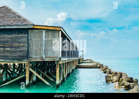 Bungalows und Häuser auf den Malediven mit wunderschönen türkisen Meer und Wolken im Himmel Stockfoto