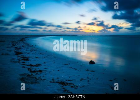 Sonnenuntergang auf den Malediven mit Reflexion der Sonne im Wasser und blau und orange farbige Wolken im Himmel Stockfoto