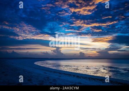 Sonnenuntergang auf den Malediven mit Reflexion der Sonne im Wasser und blau und orange farbige Wolken im Himmel Stockfoto