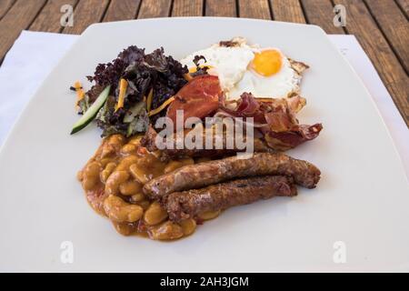 Englisches Frühstück. Frühstück serviert auf einem Holztisch mit Würstchen, Eier, Speck, Bohnen, Toast. Stockfoto