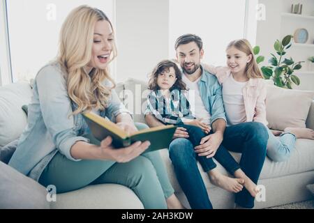 Foto von großen Familie zwei Kinder bequem sitzen Sofa hören Mumie lesen Lieblings Märchen Stockfoto