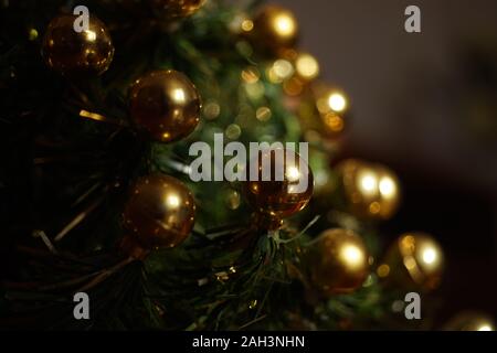 Weihnachtsbaum mit goldenen Kugeln in dunklen Zimmer Stockfoto