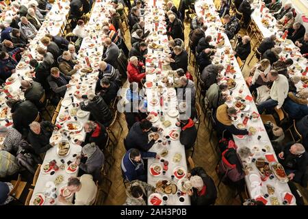 Sopot, Polen. 24 Dez, 2019. Über 200 Menschen bei den Weihnachtsabend Mahlzeit in Sopot, Polen am 24. Dezember 2019 Traditionelle polnische Heiligabend Essen nahm, wurde von der Caritas Polen christliche Nächstenliebe Organisation organisiert. Personen ein spezielles Wafer beim Austausch von Weihnachtsgrüße. Obdachlosen und Armen wurden mit traditionellen polnischen Bigos, Pierogi, Brot ergötzte und Kuchen Credit: Vadim Pacajev/Alamy leben Nachrichten Stockfoto