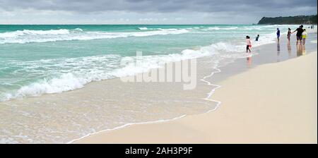 Der Provinz Aklan Boracay, Philippinen - Dezember 3, 2019: Nur wenige Menschen zu Fuß entlang der weißen Strand genießen das stürmische Wetter während der Regenzeit Stockfoto