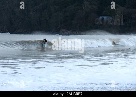 Surfer an Oxwich Bay mit St Illtyds Kirche in Woodland Hintergrund, Gower Stockfoto