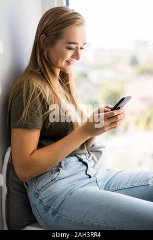 Wunderschöne junge Frau, die E-Mails abrufen und senden von SMS-Nachrichten auf Mobiltelefonen Stockfoto