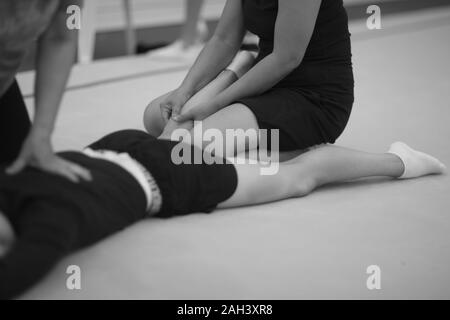 Manipulation an der Wirbelsäule und Massage der Beinmuskulatur auf die TURNERIN nach dem Training Stockfoto