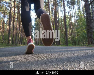 Füße eines Läufers. Junges Mädchen läuft in den Wald. Close-up von Sneakers. Helathy Lebensstil. Stockfoto