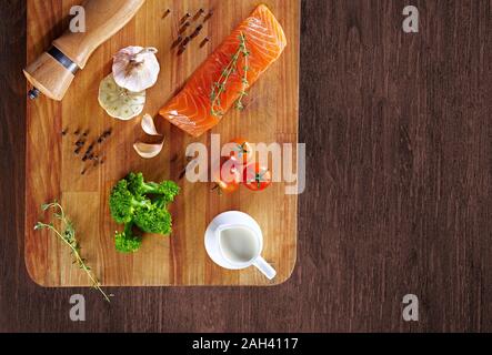 Set von gesunden Krebsnahrung auf Holztisch. Roter Lachsfisch, Brokkoli, Knoblauch, Milch, Pfeffer und Tomaten verstreut um den Tisch. Gesunde Mahlzeit Stockfoto