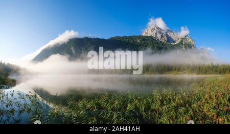 Deutschland, Bayern, Mittenwald, dicker Nebel schweben über Ferchensee See mit wettersteinspitzen Berg im Hintergrund Stockfoto