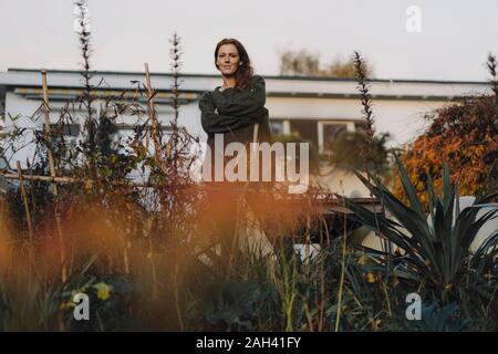 Frau, die vor ihrem Haus, Lookig am Garten Stockfoto