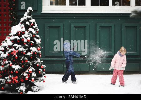 Geschwister in eine Schneeballschlacht an Weihnachten Zeit Stockfoto