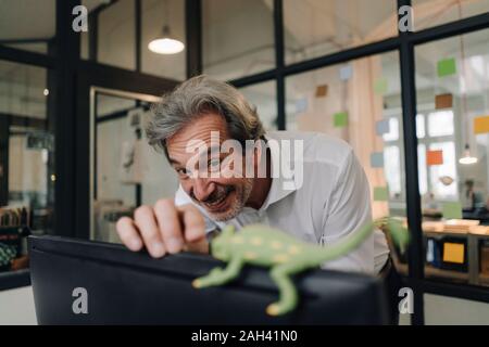 Gerne älteren Geschäftsmann mit Chameleon Figur im Büro Stockfoto