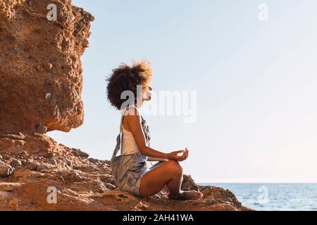 Junge Frau Meditation am Strand Stockfoto